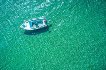 Aerial photo of motorboat tied up in turquoise sea water, Greece